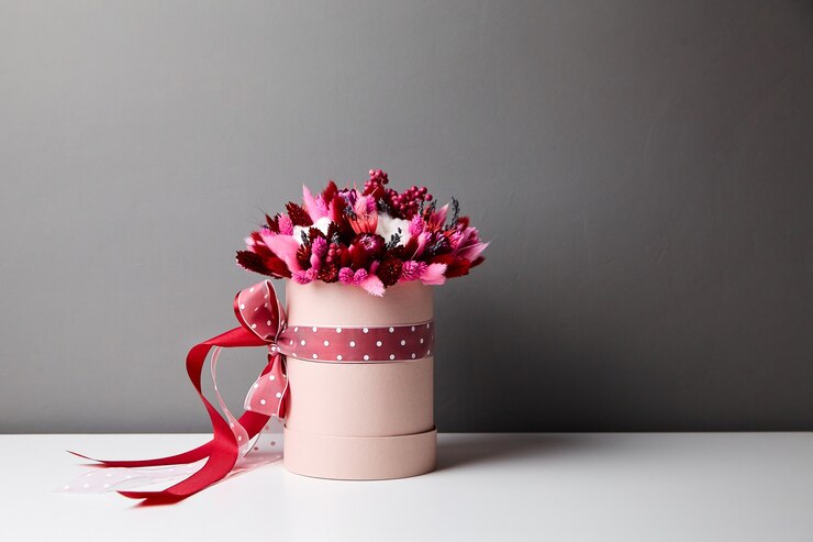 Ramo de flores secas con pastos en caja de sombrero redonda rosa