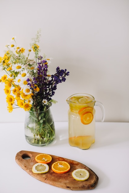 Ramo de flores silvestres naturales en florero y limonada casera con naranjas y limones