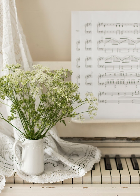 Ramo de flores silvestres en piano blanco con notas. Foto retro