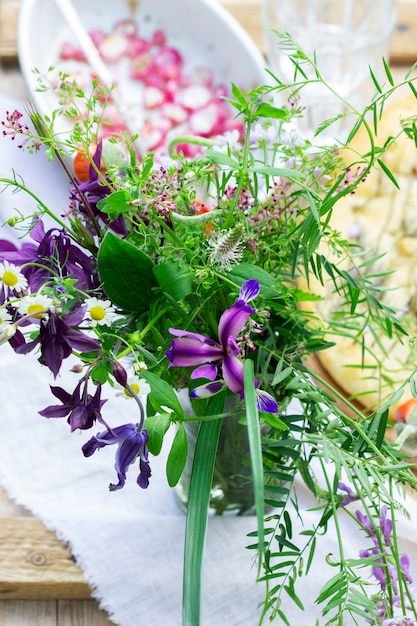 Un ramo de flores silvestres, rábano al horno y focaccia sobre una mesa de madera. Estilo rústico, enfoque selectivo.