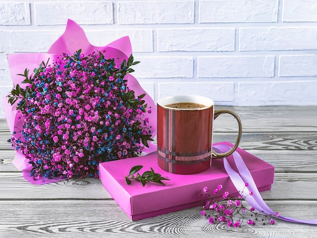 Un ramo de flores y una taza de café en un libro rosa.