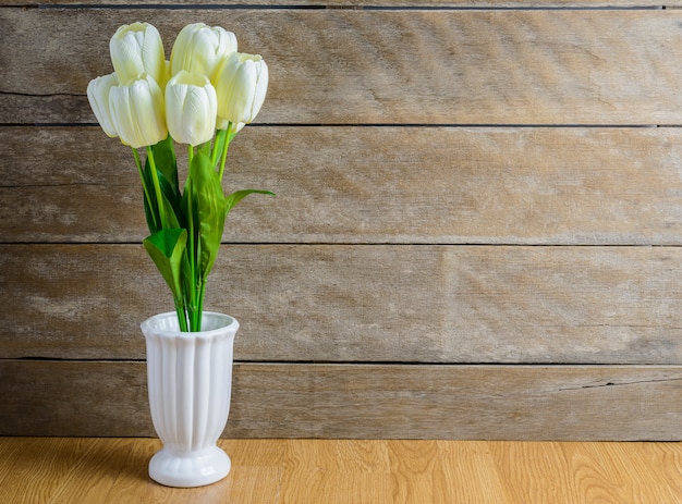 Ramo de flores de tulipán blanco en florero sobre suelo de madera