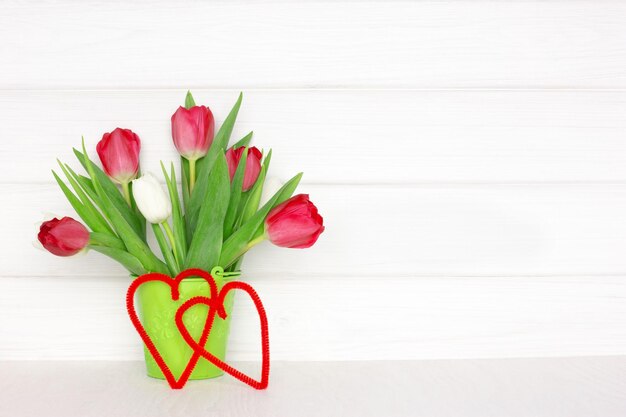 Ramo de flores de tulipán con dos corazones en la mesa de madera Fondo rústico de primavera