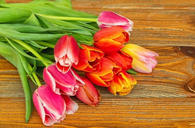 Ramo de flores de tulipán en superficie de madera marrón