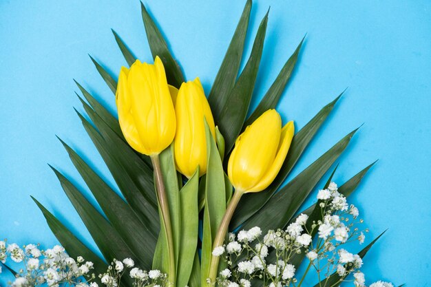 Ramo de flores de tulipanes y gypsophila sobre un fondo azul hola primavera a partir del 8 de marzo