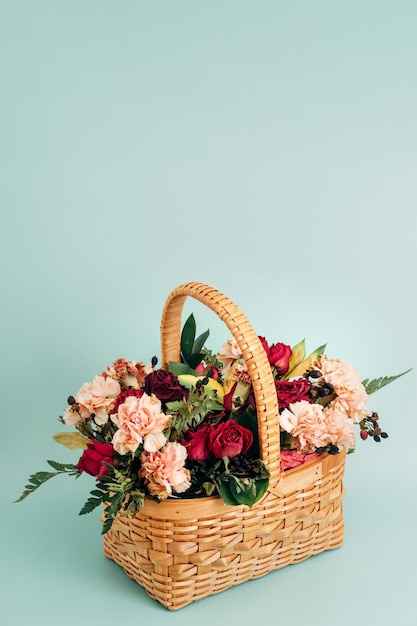 Un ramo de flores de verano en una cesta de mimbre se alza sobre un delicado fondo azul