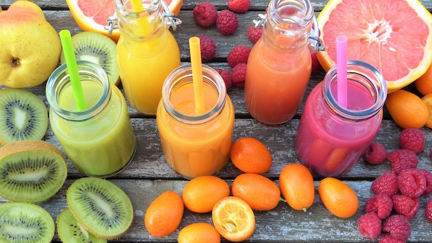 un ramo de frutas en una mesa de madera con una botella de jugo y frambuesas