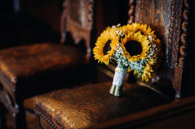 Un ramo de girasoles de boda se encuentra en una silla antigua