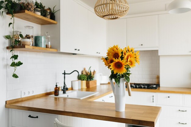 Ramo de girasoles en jarrón en la cocina Vista en cocina moderna simple blanca en estilo escandinavo