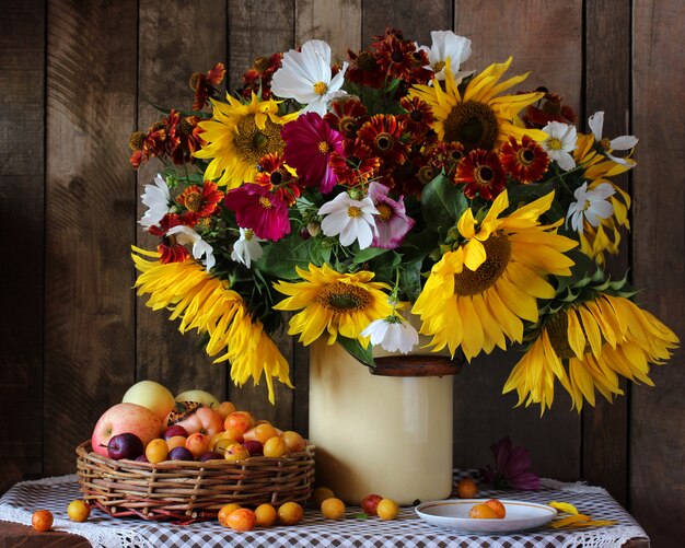 Ramo con girasoles, manzanas y ciruelas.