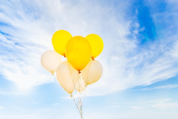 Ramo de globos amarillos y blancos en concepto de cielo azul de regalo de celebración