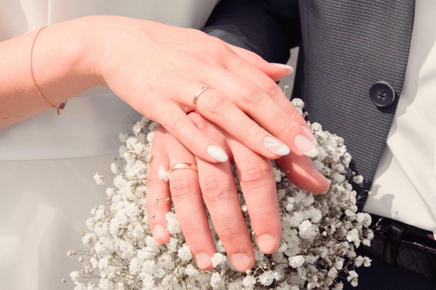 Ramo de gypsophila de color blanco con un par de manos con anillos de boda para una ceremonia de boda de enfoque suave