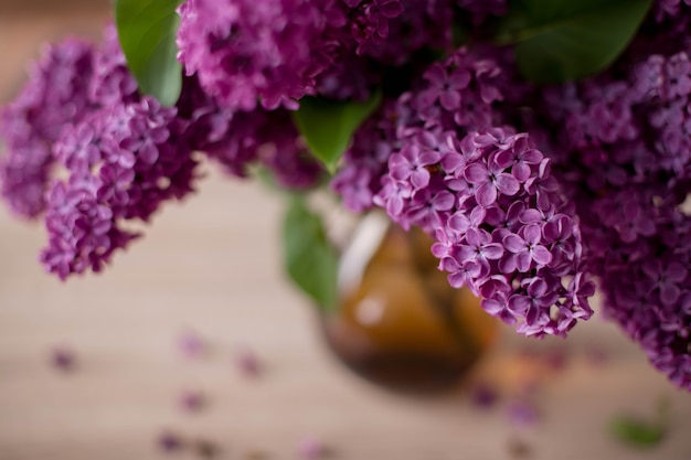 Ramo de hermosas flores de primavera de color lila en un jarrón sobre una mesa de madera, decoración del hogar en un estilo rústico. De cerca. Enfoque selectivo.