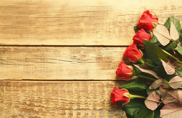 Ramo de hermosas rosas rojas sobre fondo de madera