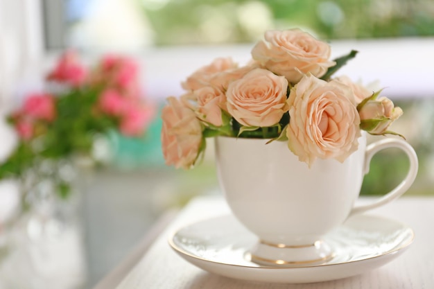 Ramo de hermosas rosas en una taza sobre una mesa