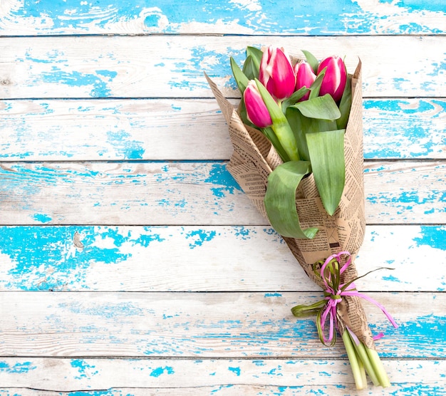 Un ramo de hermosos tulipanes en el antiguo fondo de madera azul. Vista superior. Tarjeta de felicitación.