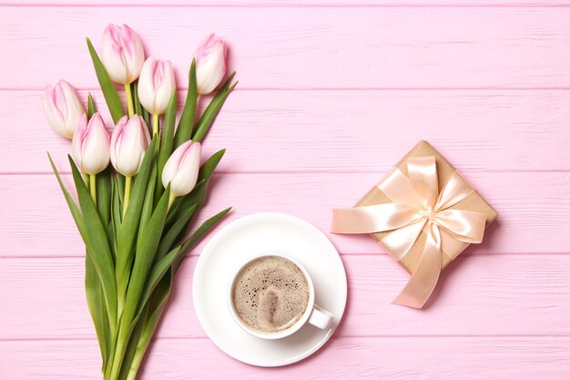 Un ramo de hermosos tulipanes y un regalo en una vista superior de fondo de madera