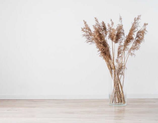 Ramo de hierba seca moderno y elegante en jarrón de vidrio sobre un suelo claro de madera en una habitación de estilo escandinavo Regalo boho art deco para aniversario cumpleaños día de la madre Espacio libre para texto