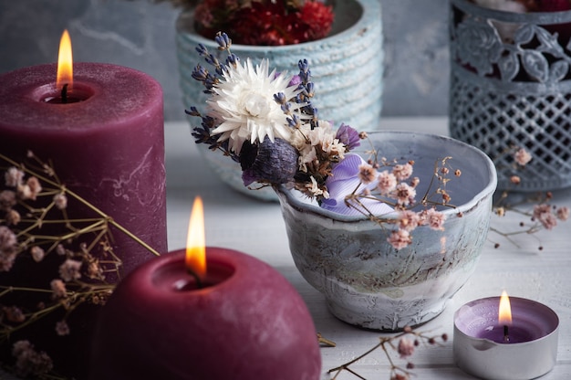 Ramo de lavanda de flores secas en florero sobre mesa de madera blanca y velas encendidas. Para saludo, invitación, tarjetas de cumpleaños.