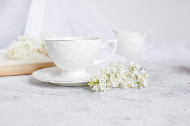 Un ramo de lilas blancas, una taza de café y un libro viejo.