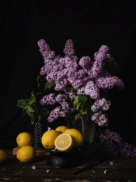 Un ramo de lilas se sienta en una mesa con limones.