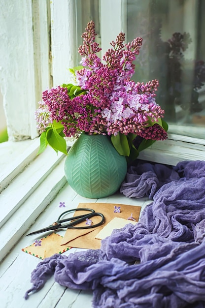 Un ramo de lilas, sobres viejos y tijeras en el viejo alféizar de la ventana, enfoque selectivo.