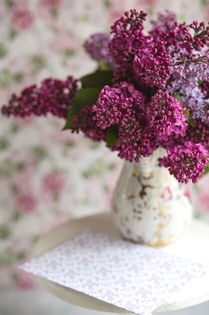 Ramo de lilas violetas en un jarrón. Naturaleza muerta con ramas florecientes de color lila en jarrones. Maqueta de tarjeta de felicitación. Espacio para texto.