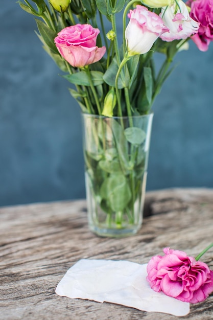 Ramo de lisianthus en una mesa de madera con nota en blanco