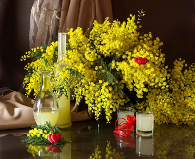 El ramo de mimosa y las botellas de licor en la mesa de cerca.