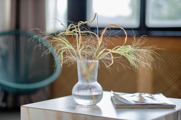 Ramo minimalista de flores secas en un jarrón de vidrio con agua al fondo de un hermoso interior