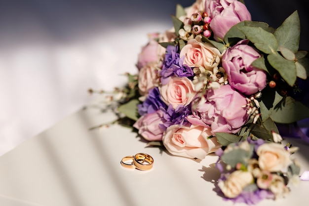 Ramo de novia y anillos sobre un fondo claro Concepto de boda