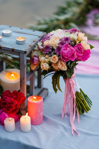 Ramo de novia entre decoración con velas y flores frescas.