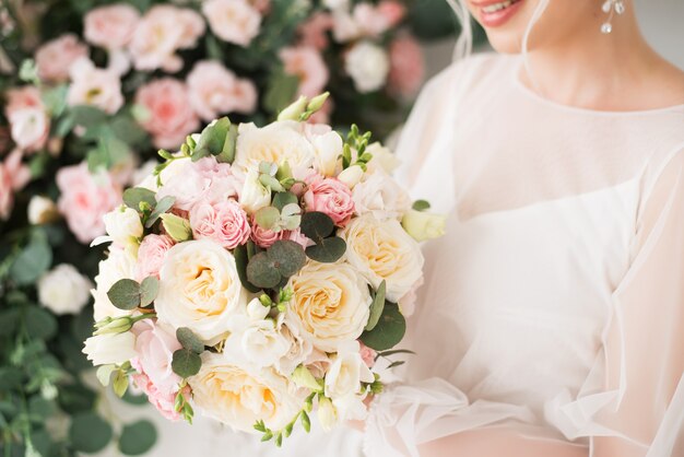 Ramo de novia en delicadas flores en manos de la novia. Rosas rosadas y crema