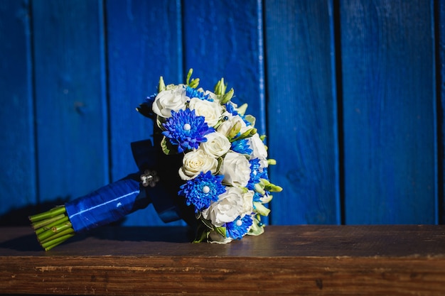 Ramo de novia con flores azules y blancas sobre un fondo azul