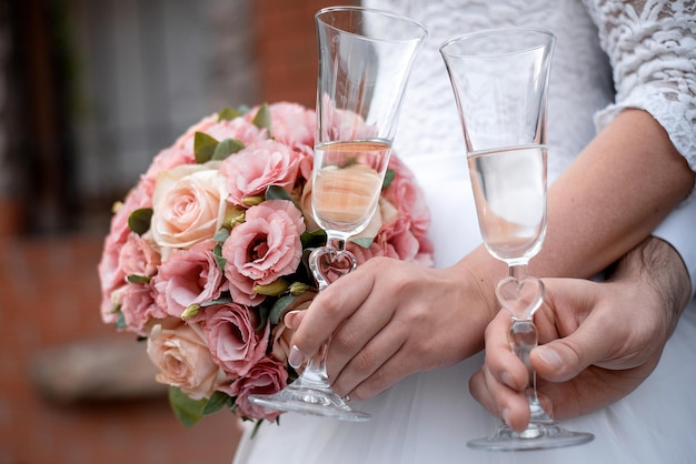 Ramo de novia en manos de la novia y el novio en la ceremonia copas de champán