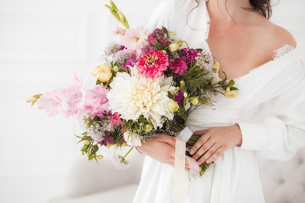 Ramo de novia en manos de la novia vestido blanco cintas estilo boho