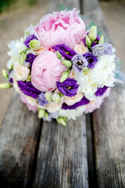 Ramo de novia de novias de peonías y rosa sobre fondo de madera