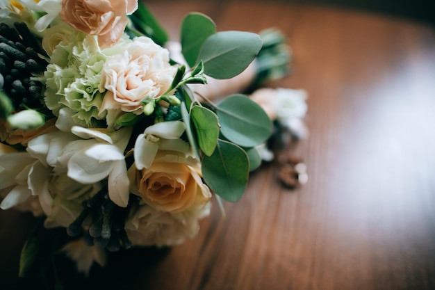 Ramo de novia en el ojal y anillos de boda sobre un suelo de madera vintagex9