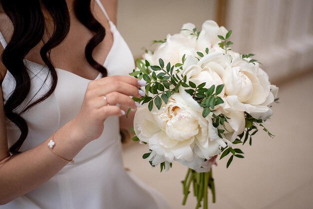 Ramo de novia de peonías blancas en manos del concepto de novia para agencias de eventos y floristería