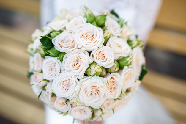 Ramo de novia de peonías blancas y rosas y rosas en manos de la novia