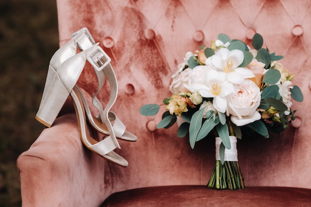 Ramo de novia con peonías y rosas en una silla y flor en el ojal. La decoración de la boda.