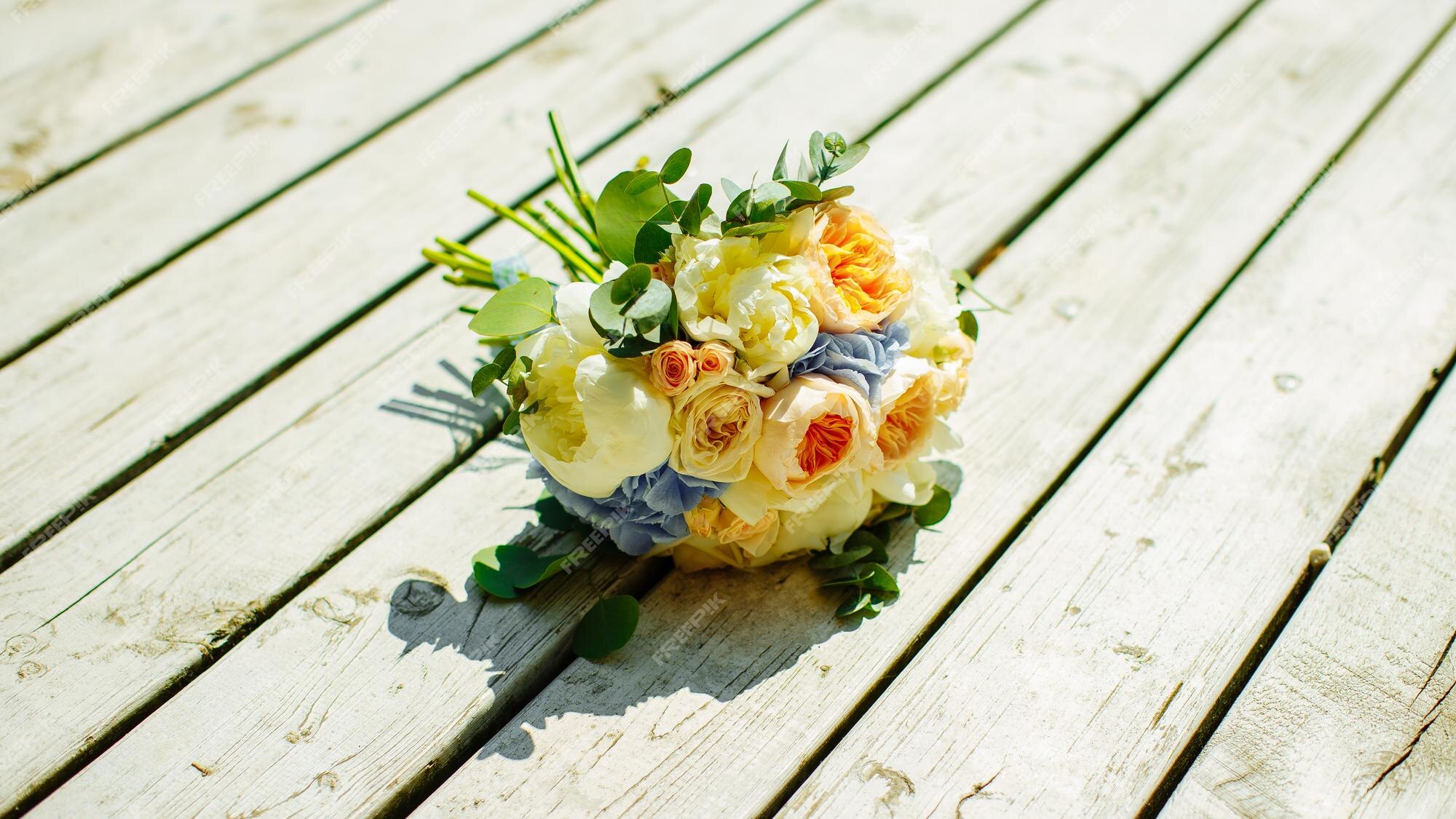 Un ramo de novia de rosas amarillas y blancas sobre tablas de madera blancas  | Foto Premium