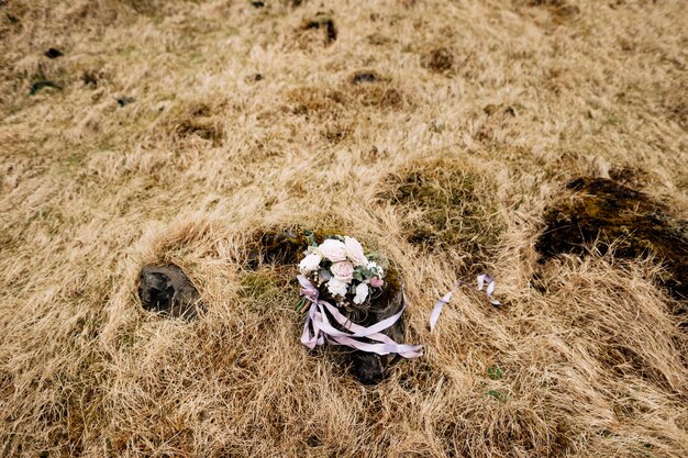 Ramo de novia de rosas blancas brunia y leucadendron en el suelo de pasto seco en islandia