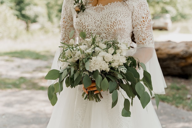 Ramo de novia con rosas blancas y hojas verdes. La novia vestida tiene ramo.