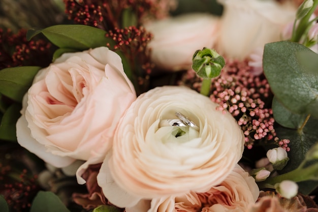 Ramo de novia con rosas y peonías rosas. Los anillos de boda se encuentran en el ramo.