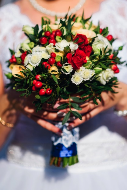 Ramo de novia con rosas rojas y margaritas blancas en manos de la novia