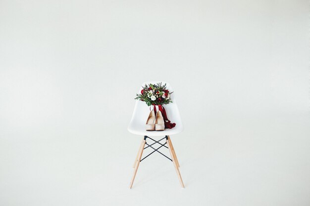 Ramo de novia en la silla de madera blanca con pared blanca.