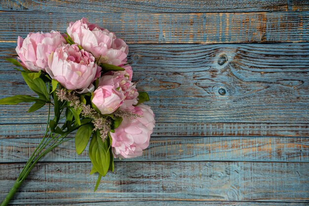 Ramo de peonías rosas sobre fondo azul de madera