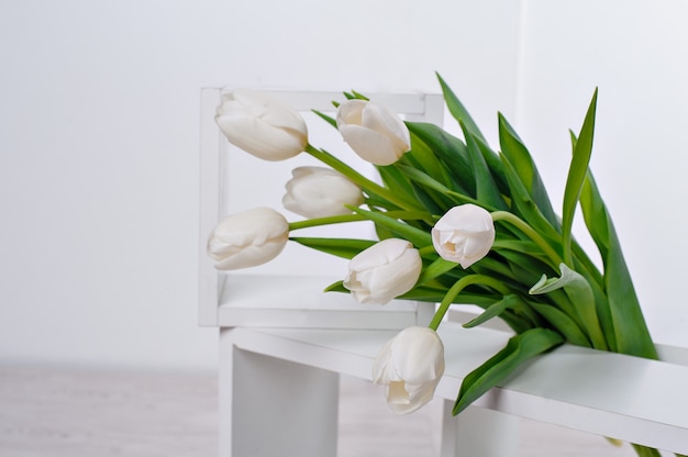 Ramo primaveral de tulipanes blancos con hojas verdes sobre blanco