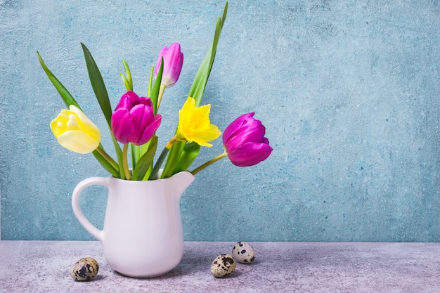 Ramo primaveral de tulipanes y narcisos en un jarrón blanco